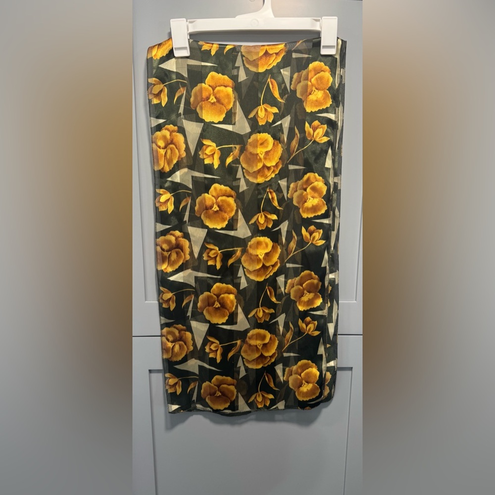 This is a green silk scarf with an orange and yellow floral print.